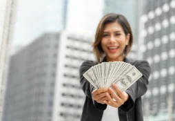 Jovem mulher segurando dinheiro do empréstimo Renner em uma cidade grande.