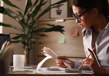 Mujer calculando gastos y revisando facturas en casa, organizando sus finanzas personales y planificando cómo usar el aguinaldo de forma inteligente.