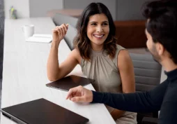 Mujer y hombre conversando sobre préstamo personal y opciones de crédito en una oficina moderna
