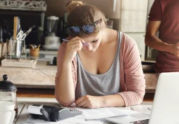 Mujer revisando cuentas y gastos en casa, preocupada por sus finanzas personales y el pago de préstamos