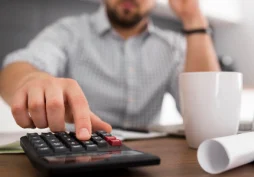 Homem calculando parcelas de empréstimo na calculadora para evitar juros altos no crédito pessoal