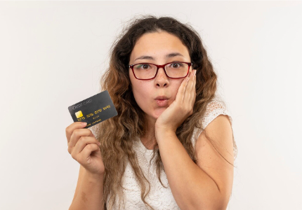 Mulher surpresa segurando cartão de crédito após ter dificuldade na aprovação de empréstimo