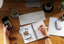 Pessoa calculando despesas com dinheiro e calculadora sobre mesa, representando controle financeiro e planejamento de gastos