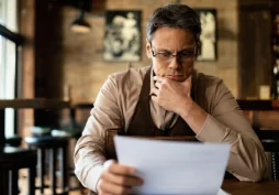 Homem analisando documento com preocupação após possível negativa de crédito ou empréstimo