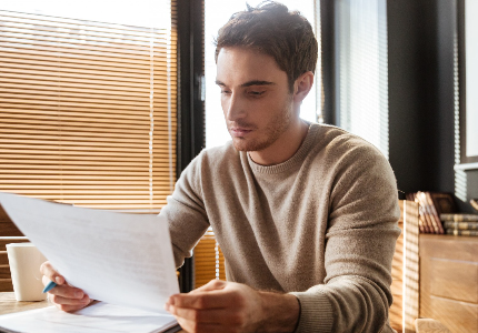 Homem analisando documento financeiro com preocupação, representando queda no score de crédito e busca por recuperação