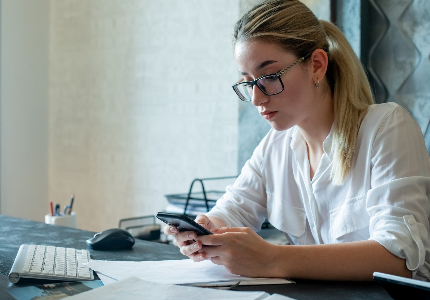 Mulher analisando celular e contas financeiras com expressão preocupada, representando uso de cheque especial e dificuldades de crédito
